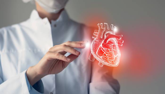 A female doctor touches the virtual image of a heart displayed before her.